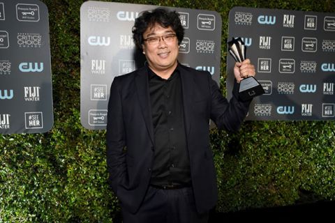 Bong Joon Ho. Korean man with dark hair wearing black jacket and shirt holding a Critics' Choice Award.
