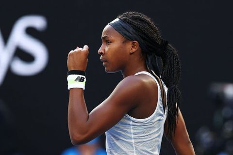 Coco Gauff. Young Black woman on tennis court wearing long braids, blue headband, white tank top and white and black wristband.