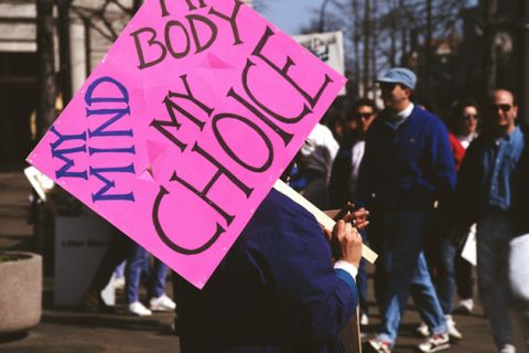Protest. A protester carries a hot pink sign that reads "My Mind, My Body, My Choice."