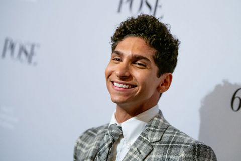 Angel Bismark Curiel. Latinx man, smiling, with short, dark curly hair wearing plaid tie and suit jacket with white shirt.