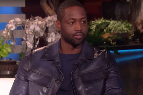 Dwayne Wade. Black man with short dark hair wearing black shirt and black leather jacket on a TV set.