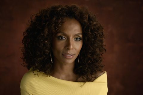 Janet Mock. Black woman with brown shoulder-length curly hair wearing a yellow top.