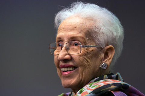 KATHERINE JOHNSON. Elder Black woman with short white hair, wearing glasses and a colorful top.