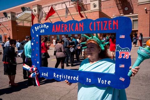 woman dressed as statue of liberty holds sign that says she became an American citizen and registered to vote.