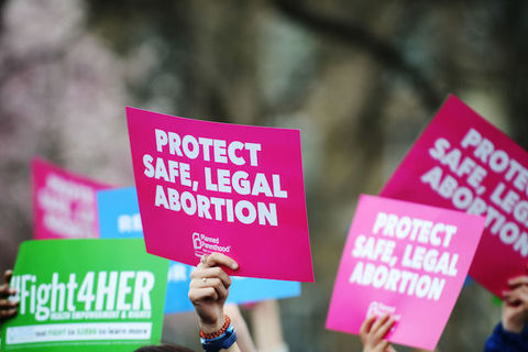 pink and green placard signs held in the air in support of abortion rights