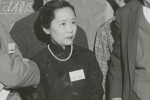 Chien-Shiung Wu. Black and white photo of Asian woman with dark hair pulled back wearing dark high-collar top with pearls and name tag.