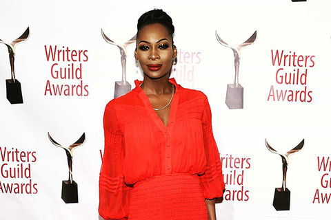 Dominique Jackson. Black woman with hair in top bun wearing a red dress on red carpet