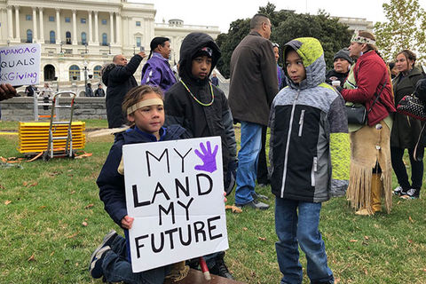 Native American Land Protest. Three young boys stand around a sign reading "My land my future."