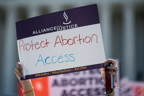 A person holds a protest sign that reads, "Protect Abortion Access"