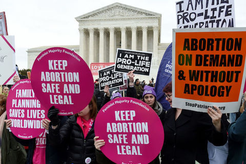 Protesters hold both pro-choice and anti-abortion signs in front of the U.S. Supreme Court.