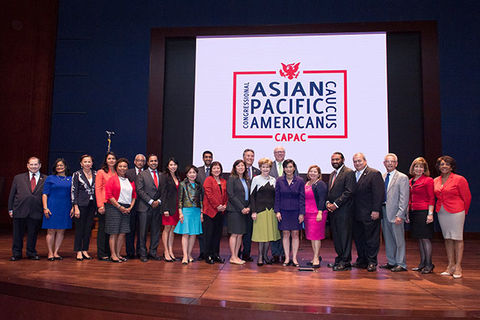 Congressional Asian Pacific American Caucus. Group of congressional employees standing on a stage in front of a blue curtain and sign reading  Congressional Asian Pacific American Caucus.