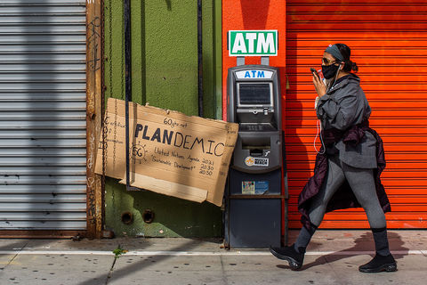 A young black woman dressed in gray and wearing a black mask, walks by the closed stores of the Boardwalk in Venice, California .