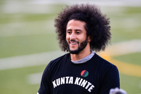 close up image of Colin Kaepernick wearing a black shirt that says kunta kinte. 