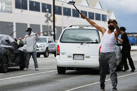 Los Angeles COVD-19. Three men wearing face masks on a highway using squeegees to clean car windows.
