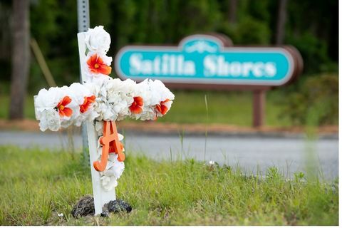 Ahmaud Arbery. A white-and-red-flowered cross and the letter "A" sits in the ground at the entrance to the Satilla Shores neighborhood where Ahmaud Arbery was shot and killed