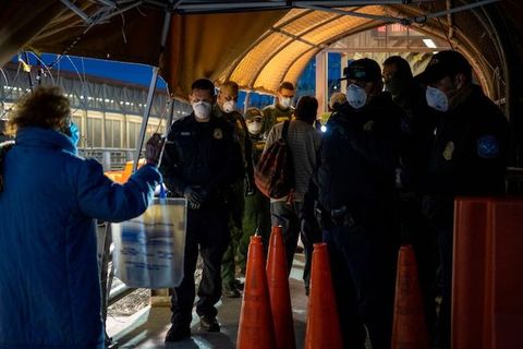Border patrol officers at the southern border wear white face masks as they check someone's ID. 