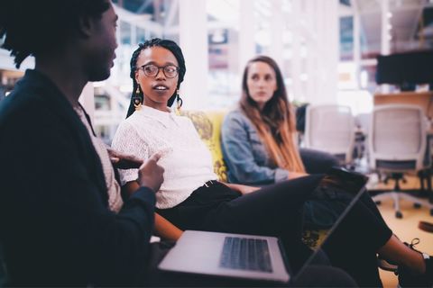 three workers. Two African American, one white worker sit in a semi circle for a meeting.