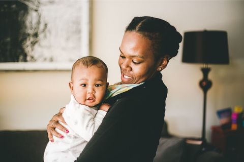 Smiling Brown skinned woman holding a lighter baby to her chest. 