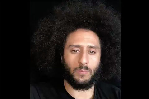 Colin Kaepernick. Black man wearing black shirt with dark Afro and dark facial hair.