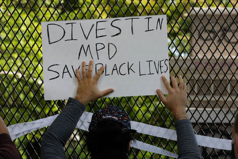 protester hold a sign that reads, "Divest in MPD"