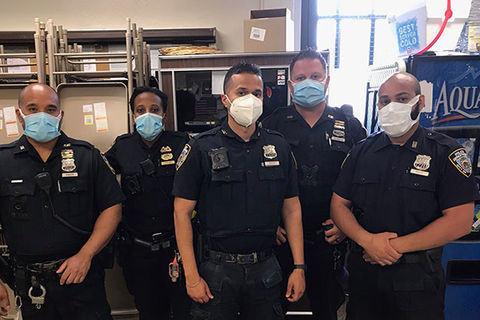 NYPD. Five officers of different races and one Black woman, in uniform, in a rec room wearing face masks, 