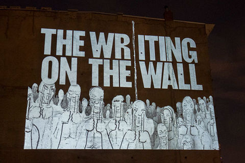 Writing on the Wall. Artwork in white letters read: THE WRITING ON THE WALL, with abstract sketches of people, over a brown wall