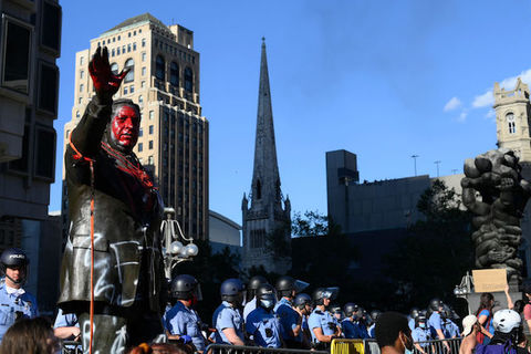 Statue of Frank Rizzo with red paint on it, and surrounded by police officers.