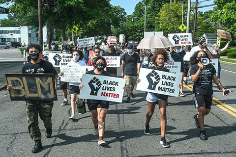 BLM Protestors. Multiracial group of young people carrying signs reading "Black Lives Matter."