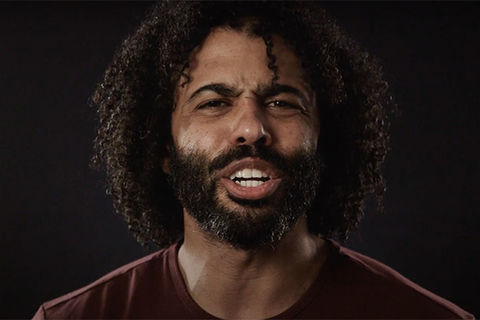 Daveed Diggs. Black man with dark curly hair and dark facial hair wearing a maroon colored top.