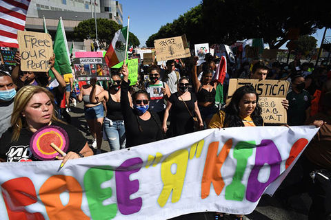 Free the Kids rally. Group of marchers hold colorful sign reading "Free R Kids."