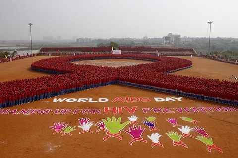 Aerial shot of people arranged as a red AIDS ribbon, as well as the words World Aids Day and Hands Up For HIV Prevention