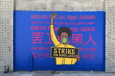 Brian-Herrera's art. Mural showing Black girl with black Afro wearing yellow and raising a fist.