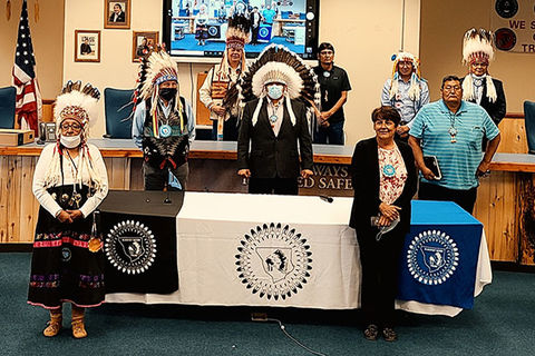 Blackfeet COVID-19- Incident Command. Nine people, some wearing feather head garments and face masks and some in Western clothing.