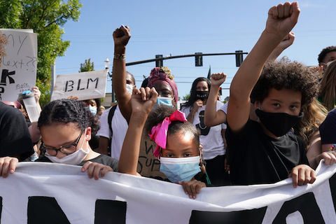 Young Black protesters hold their fists in the air during a Black Lives Matter march on August 1, 2020, in Portland, Oregon. 