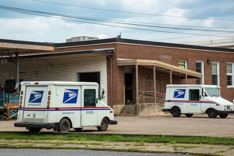 Two mail trucks are parked in an otherwise empty parking lot. 
