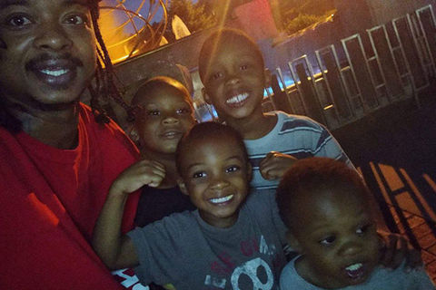 Jacob Blake and children. Black man with locs wearing red shirt in photo with four young Black boys.