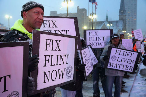 Protesters hold signs that read, Fix Flint Now and Flint Lives Matter