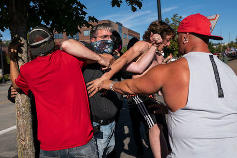 A small group of Black people and White people appear to be in a shoving match while standing outside. 