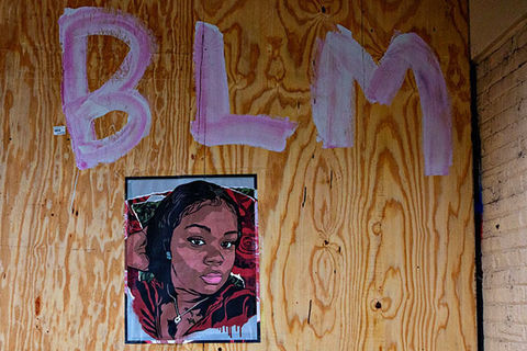 Breonna Taylor. Artwork of Black woman on a wooden board under the letters BLM.