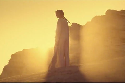 Dune. Film shot of a woman standing the bright sunlight on sand dunes.