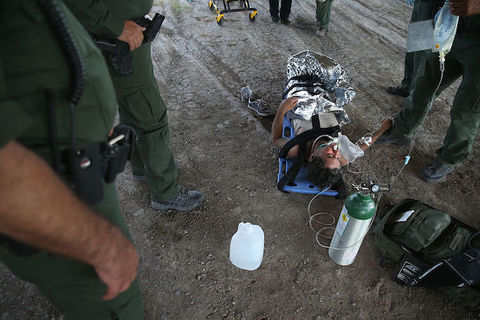 a person lies on a blue mat and is covered in silver foil as they receive an IV treatment.