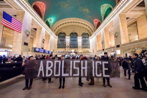 protesters hold a sign that reads, Abolish ICE