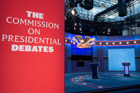 Presidential Debate stage. Red sign reads: The Commission on Presidential Debates. Stage is in the background.