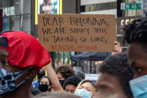Protester holds a sign that reads, "dear Breonna, we're sorry this is taking so long. "