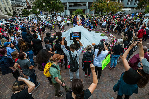 Breonna Taylor. Group of people surround a memorial.