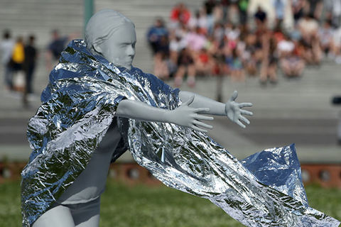Child separation. A woman mannequin wearing a foil blanket reaches out with both hands.