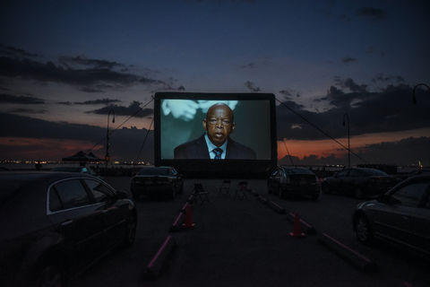John Lewis. Image of bald, elderly Black man on giant outdoor screen.
