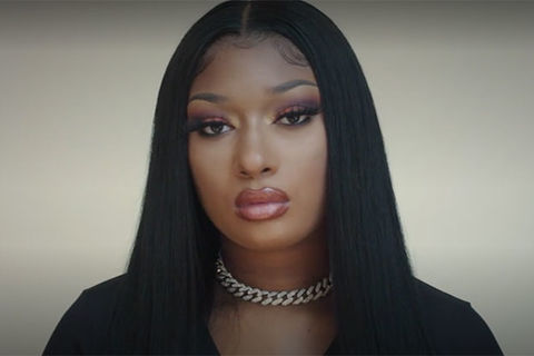Megan Thee Stallion. Black woman with long dark hair parted down the middle wearing a choker chain and black top.