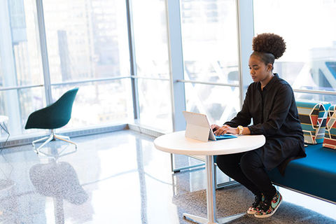 PayPal Black Latinx business. Young Black woman with pomp pomp Afro at a desk and laptop.