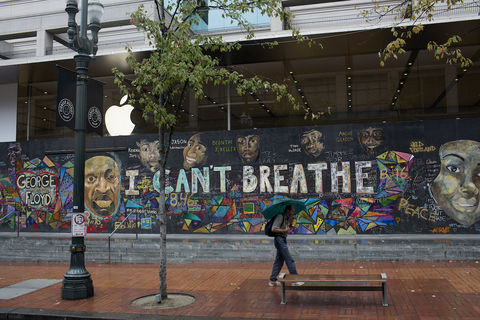 Person with umbrella walking in front of colorful I Can't Breathe mural 